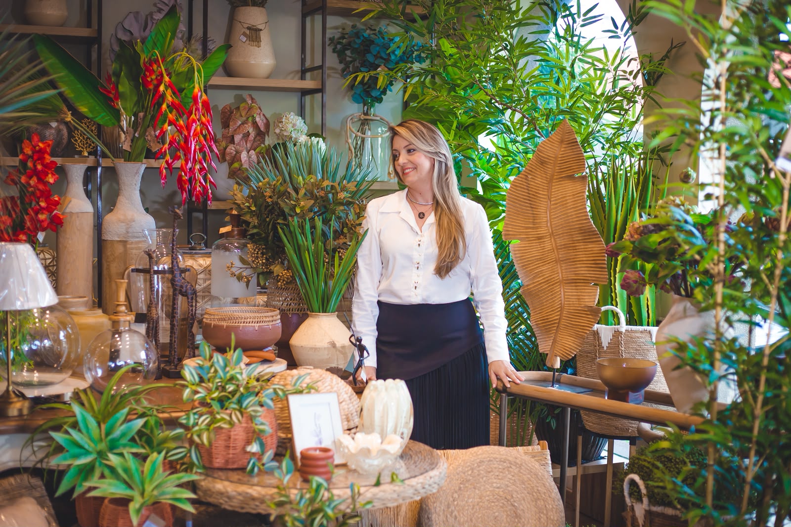 Maria Manfrim em seu ateliê de decoração, cercada de plantas e objetos de decoração